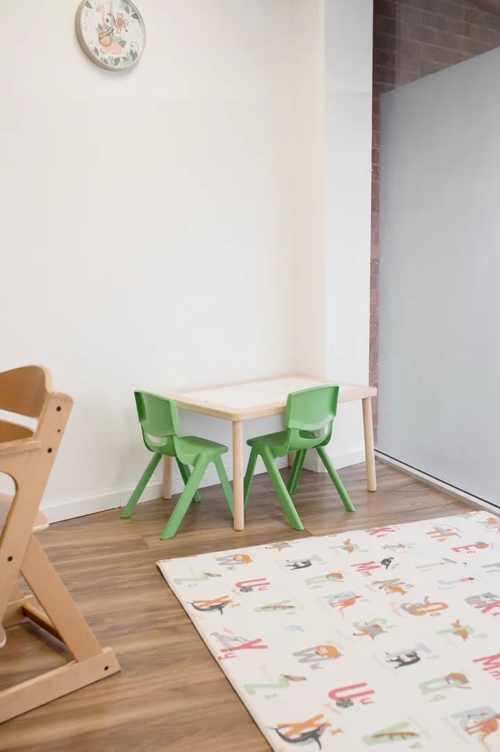 A bright therapy room at the Ashgrove clinic with a child-sized table, green chairs and an alphabet mat