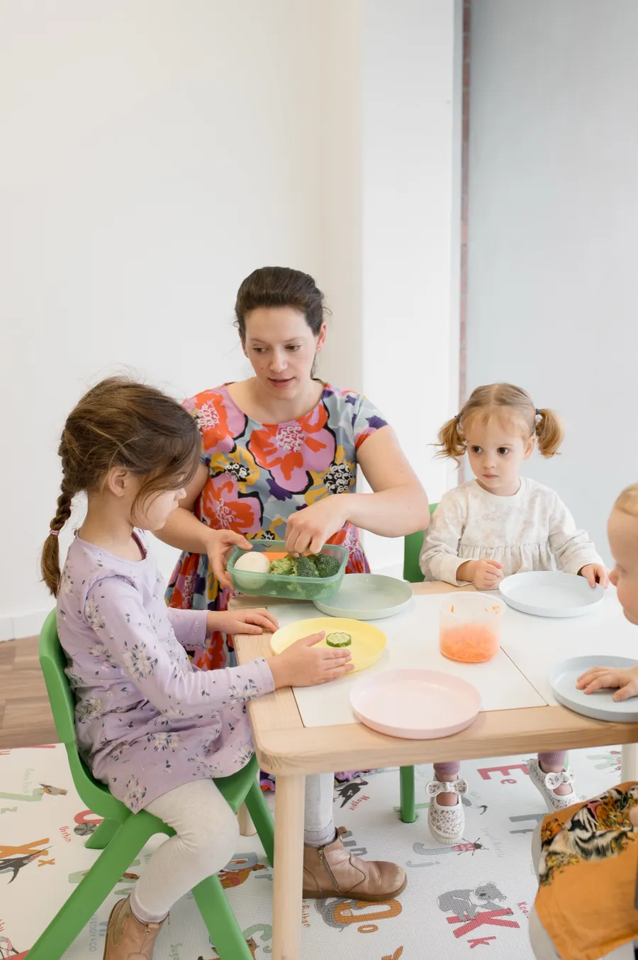 A Sound Beginnings speech pathologist offering vegetables to three young children around a mealtime table