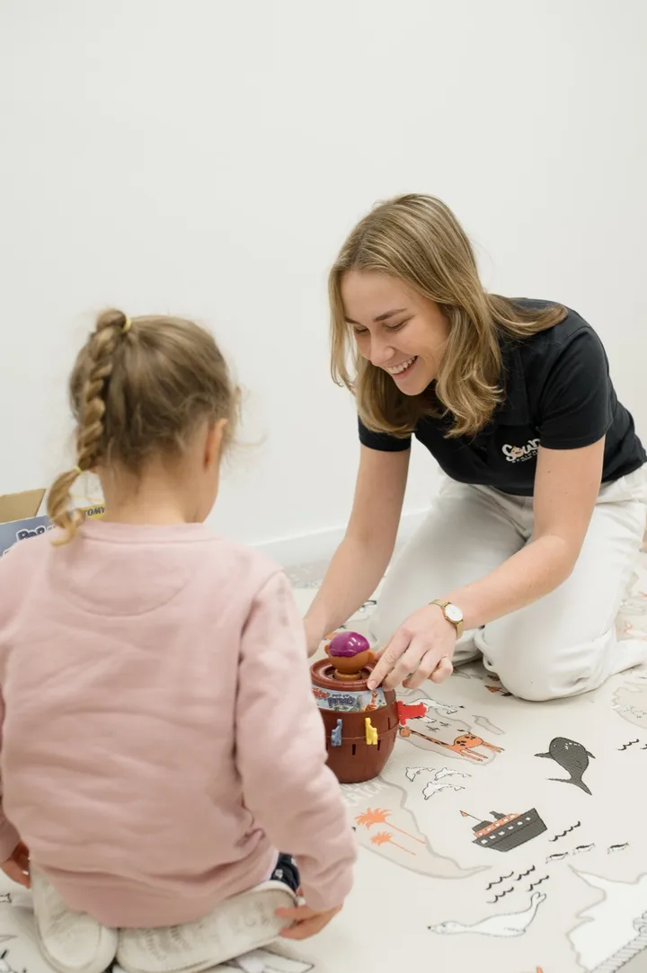 A therapist and child playing a language game together on the floor