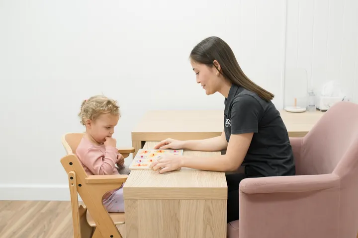A speech pathologist working one on one with a child at a therapy table