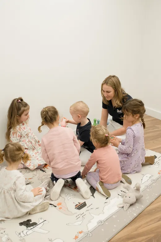 A therapist leading a small group session with children on a play mat