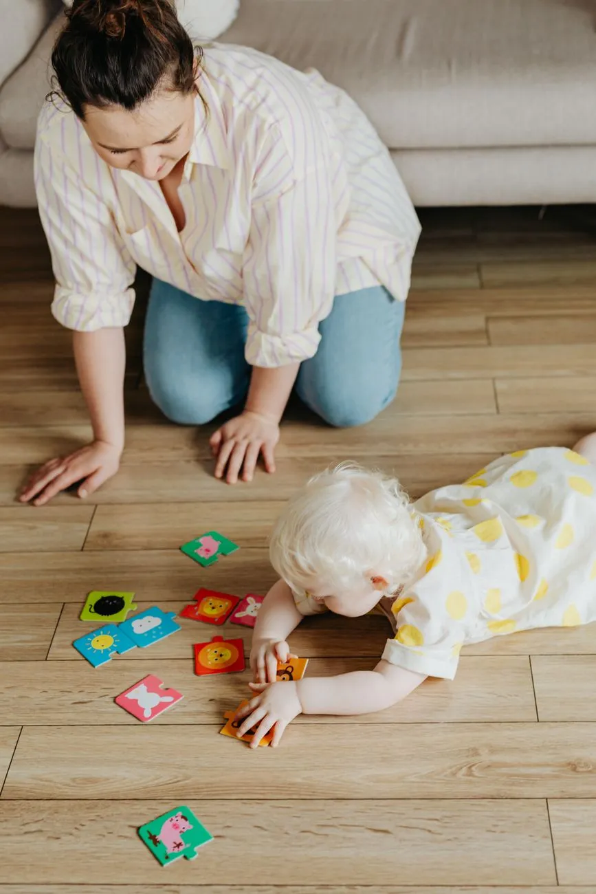 An adult and a young child playing a colourful picture-card game together on the floor